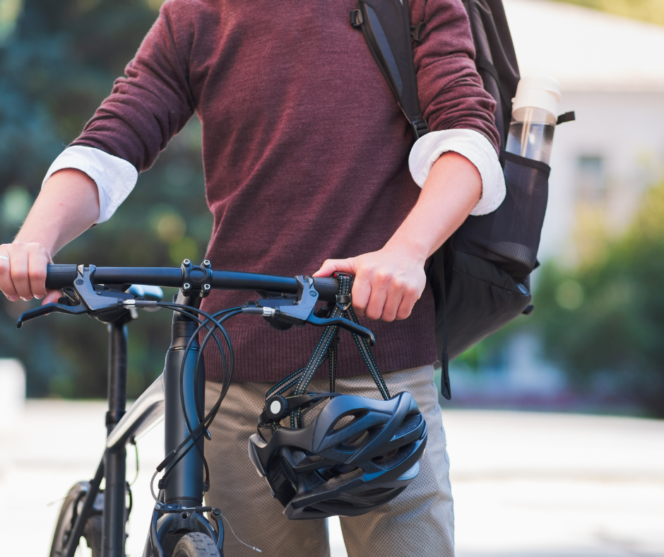 Vélotaffeur tenant un vélo et un casque, avec un sac à dos équipé d'une gourde.