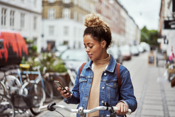 Une cycliste vélotaffeuse qui consulte son téléphone dans la rue