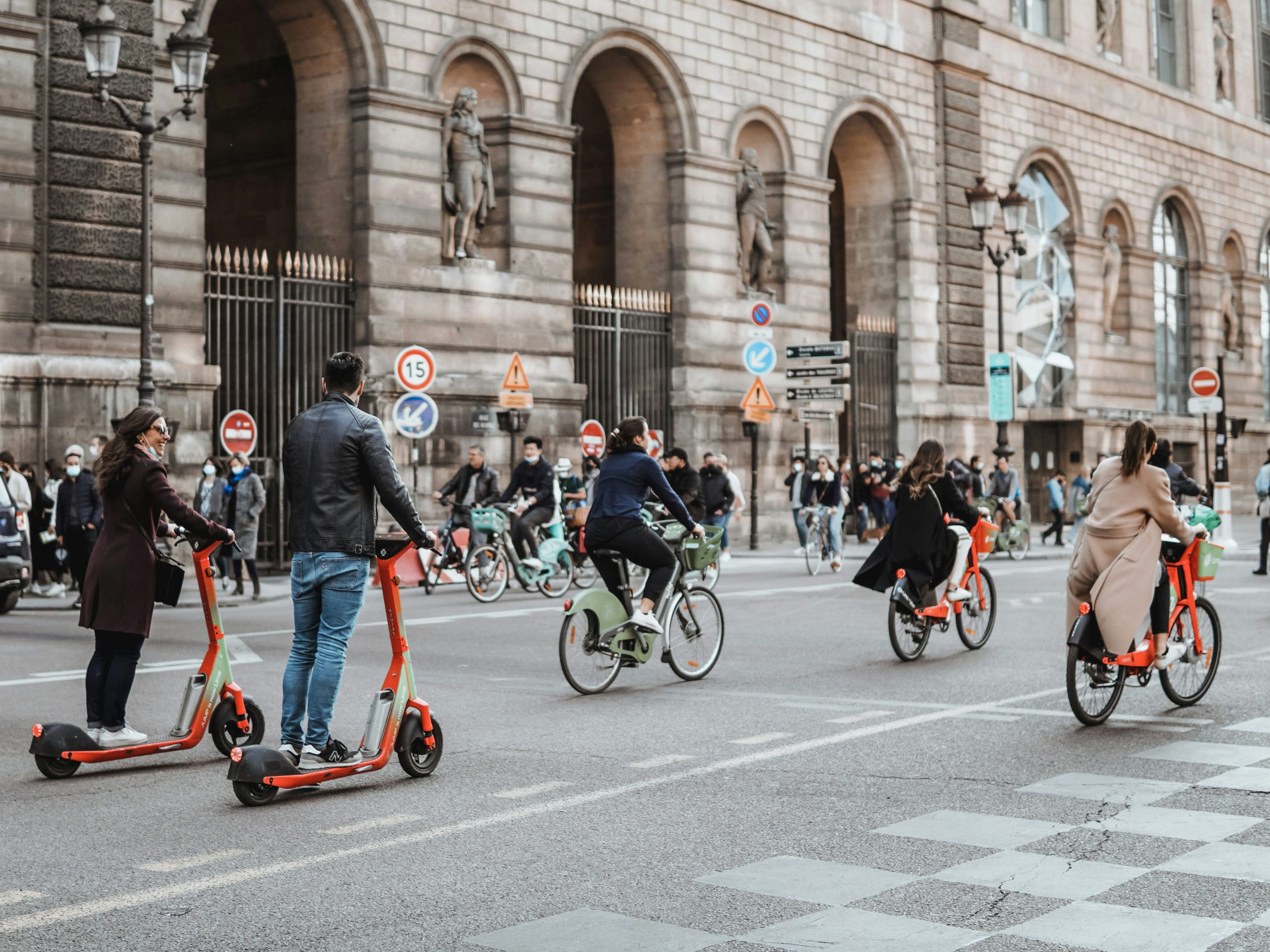 Des personnes se déplaçant en ville à vélo ou en trottinette