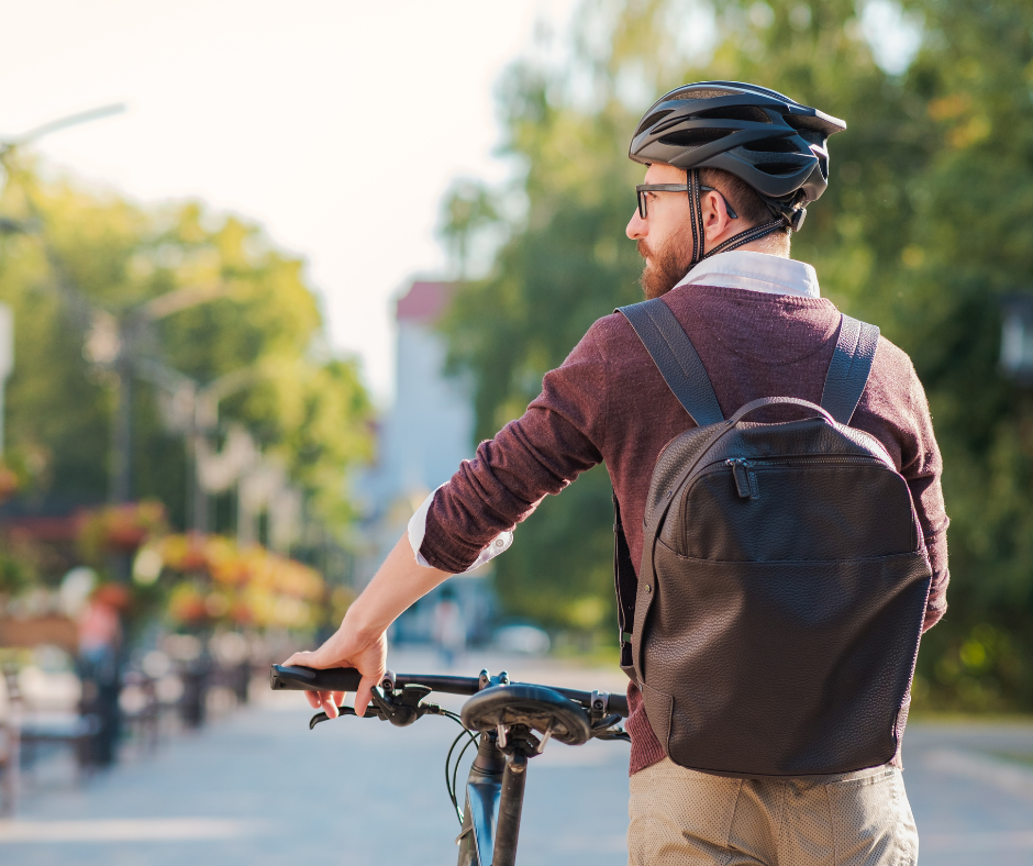 Personne avec un casque et un sac à dos qui tient un vélo