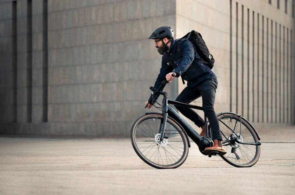 Un vélotaffeur en plein trajet urbain, équipé d'un casque et d'un sac à dos.