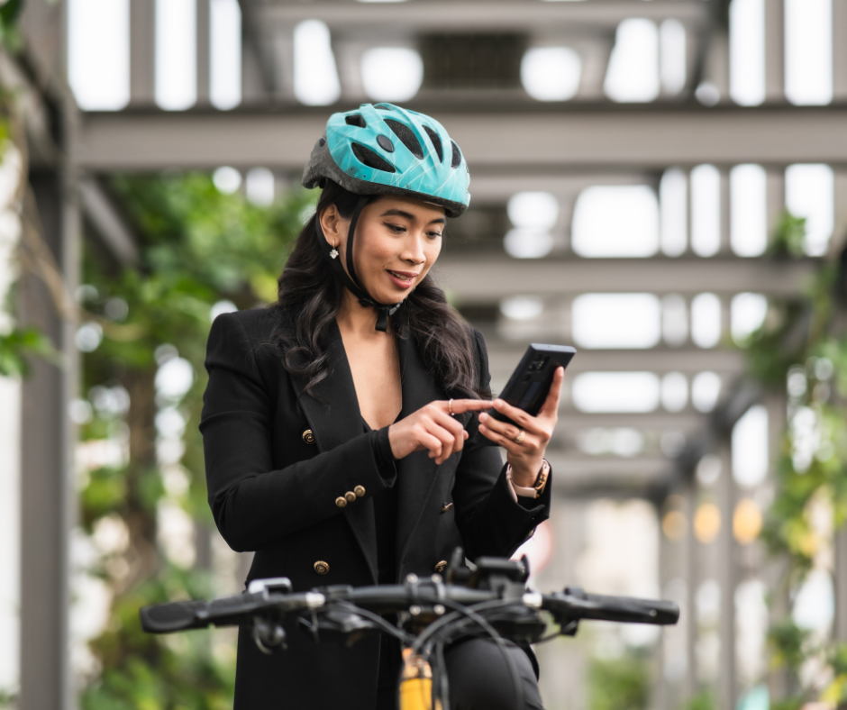 Une vélotaffeuse vérifie son itinéraire sur son smartphone, casque sur la tête.