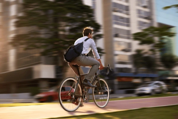 Un homme en costume roule à vélo sur une piste cyclable en ville.