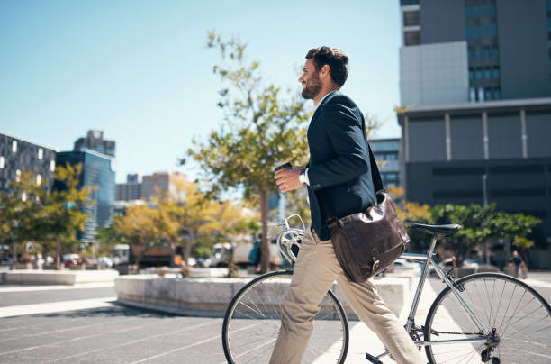 Un homme en costume marche à côté de son vélo dans un cadre urbain.