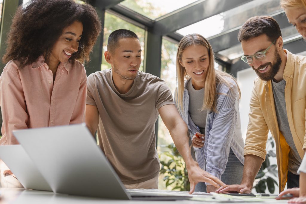 Un groupe de collègues souriants collaborant autour d'une table dans un espace lumineux